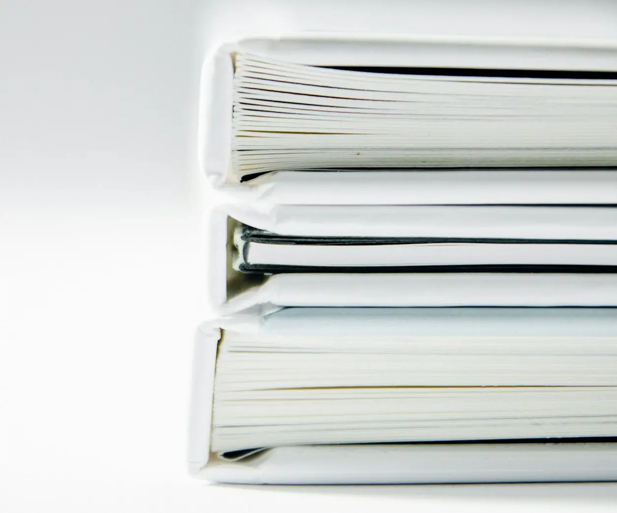 A stack of thick folders on a white surface